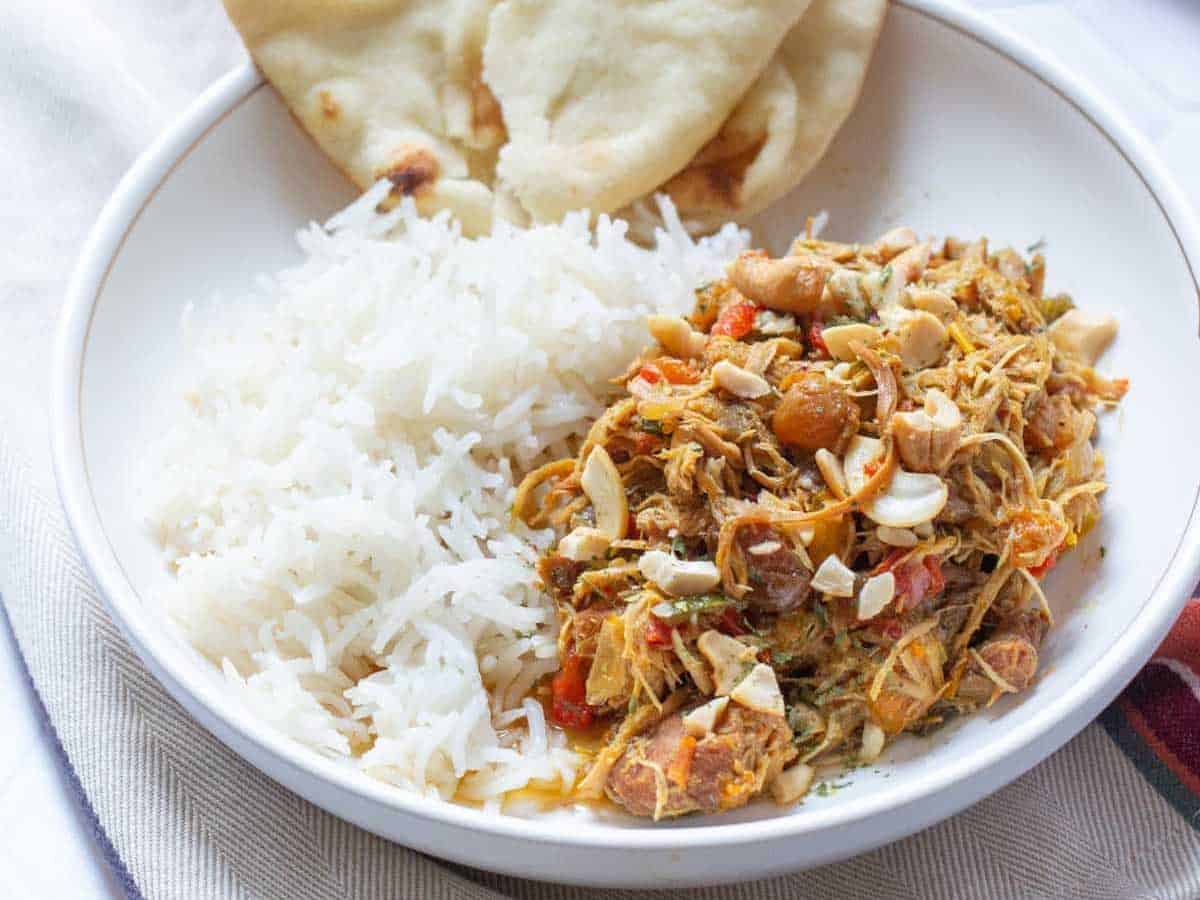 bowl of curried chicken with rice and naan