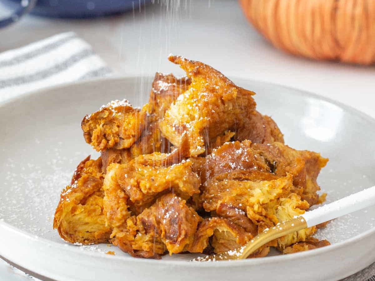 sprinkling powdered sugar on pumpkin french toast casserole