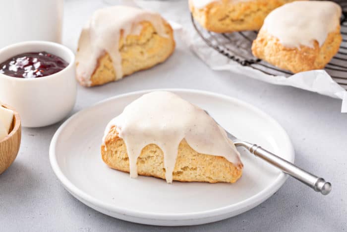 A glazed vanilla bean scone on a white plate.