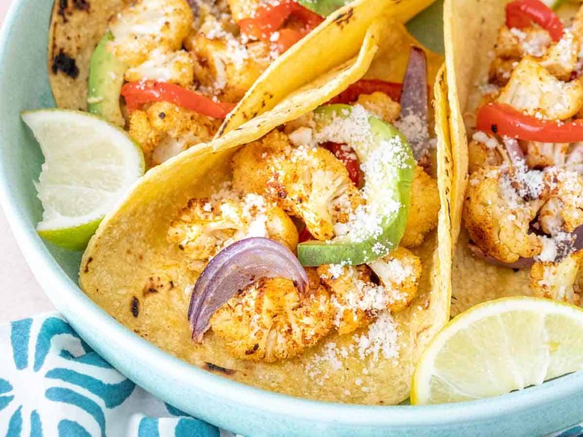 Plate of cauliflower tacos with toppings on a blue plate.