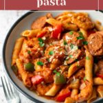 A bowl of jambalaya pasta with penne, sausage, shrimp, and bell peppers, garnished with parsley.