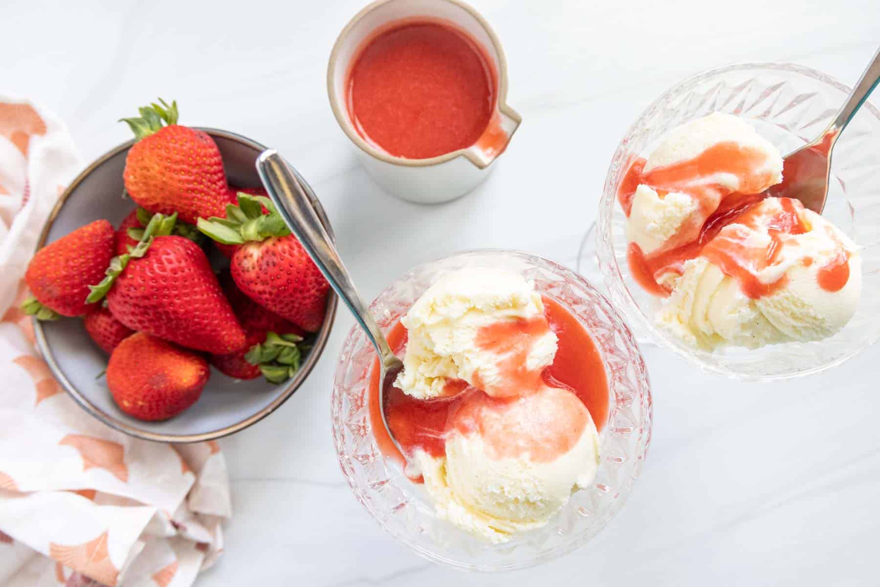 Bowls of vanilla ice cream with strawberry coulis poured over the top.