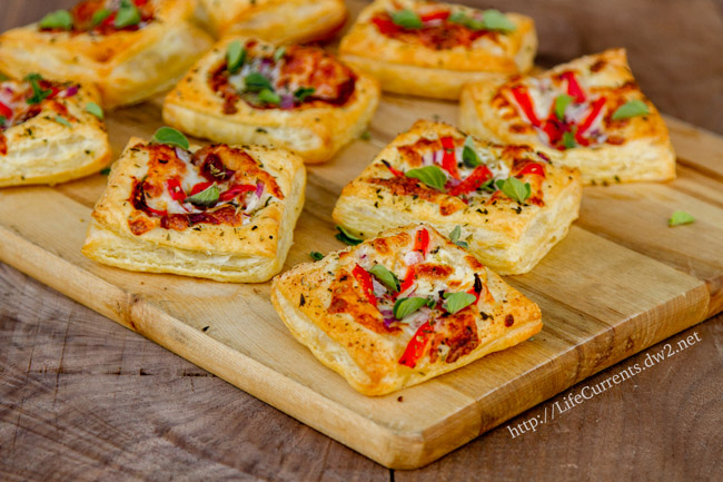 Pizza tarts on a wooden cutting board.