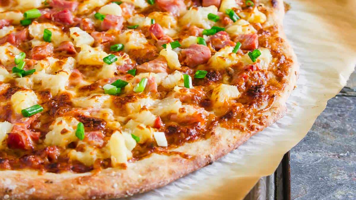 A BBQ pineapple pizza on parchment paper.