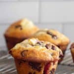 Close-up of chocolate chip muffins cooling on a wire rack, set against a tiled background.