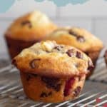 Three strawberry cheesecake muffins on a cooling rack.