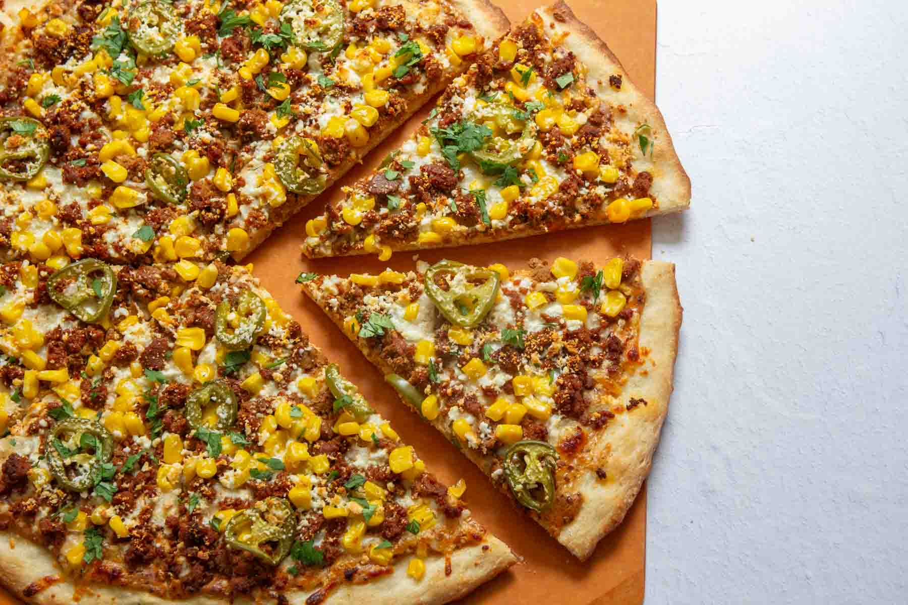 Chorizo corn pizza sliced on a pizza peel.